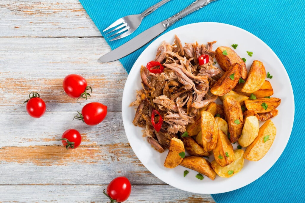 Рваная свинина с картофельными дольками на тарелке