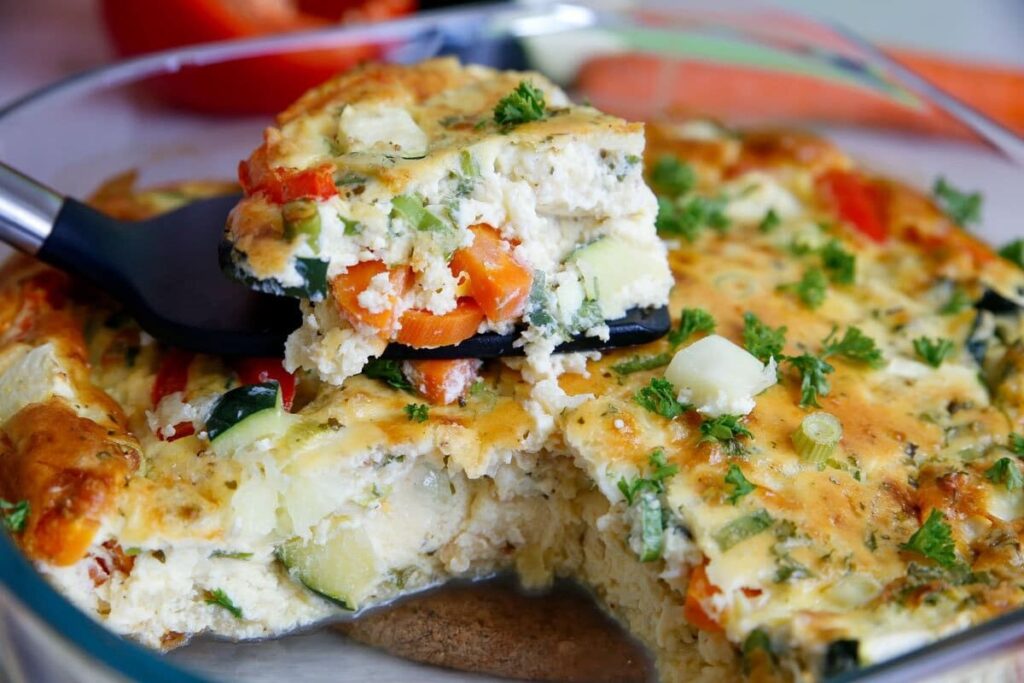 Нарезанная овощная фриттата с кусочками кабачка, перца и зеленью.