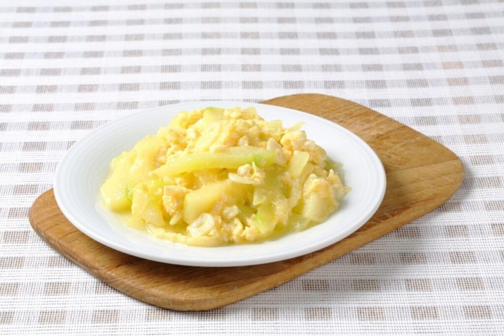 Яичница-болтунья с кусочками кабачка на светлой тарелке.