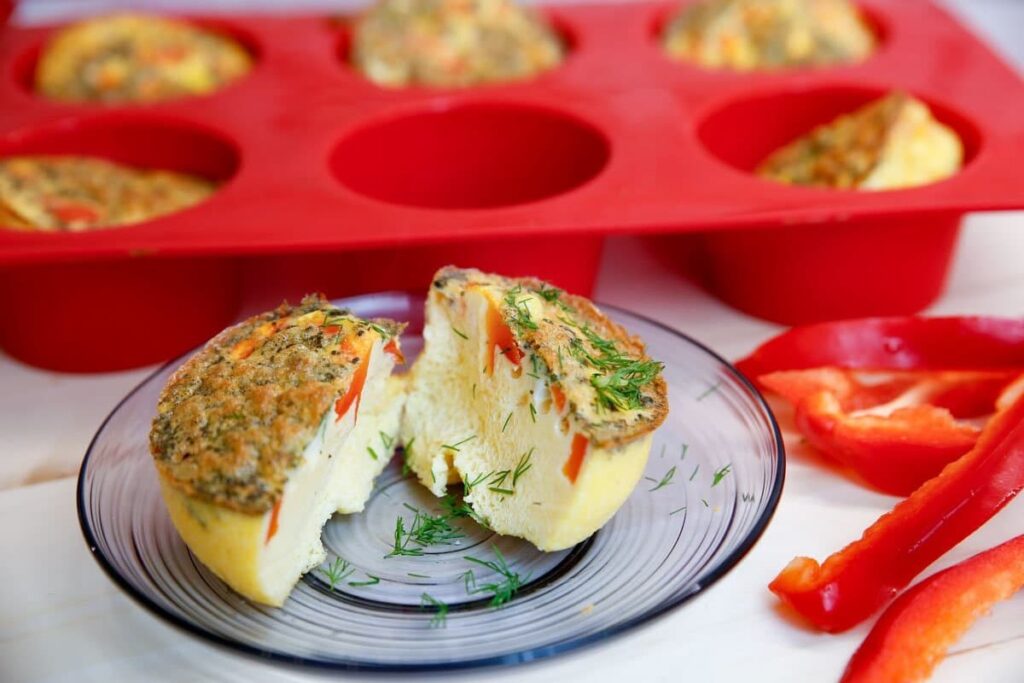 Яичные маффины с кусочками красного перца и зеленью на тарелке