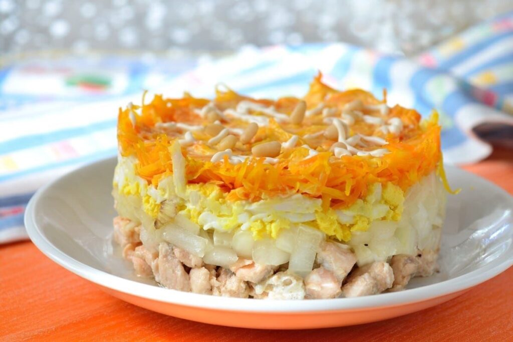 Слоёный салат с рыбой, морковью, яйцами и кедровыми орехами