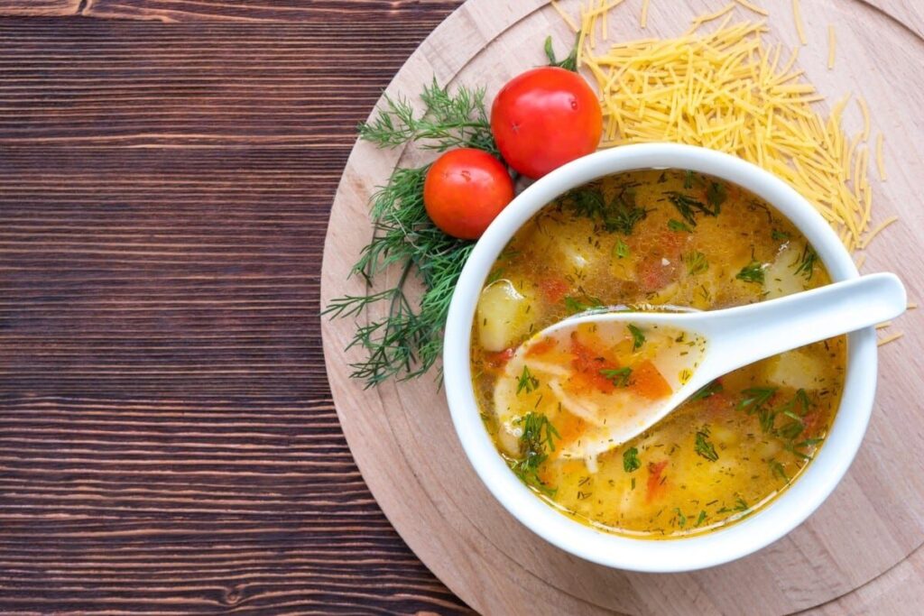 Куриный суп с картофелем, вермишелью и зеленью в светлой миске
