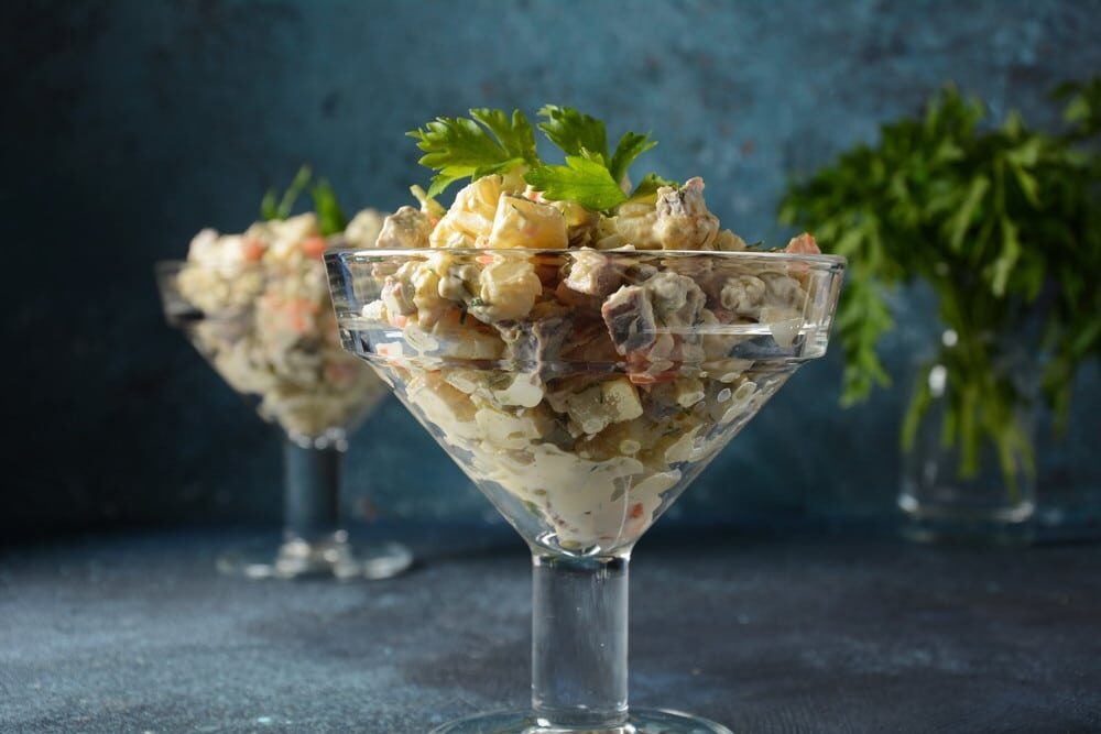 Оливье с мясом, яйцом и зелёным горошком в стеклянных креманках