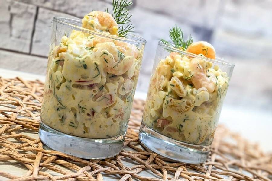 Салат из креветок и яиц с оранжевыми дольками мандарина подан в двух стаканах.
